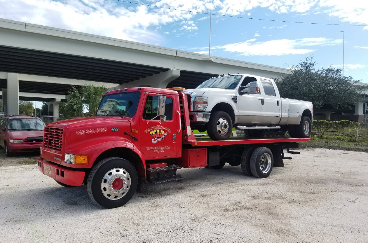 Heavy-duty pickup truck on a flatbed tow truck arriving at the shop